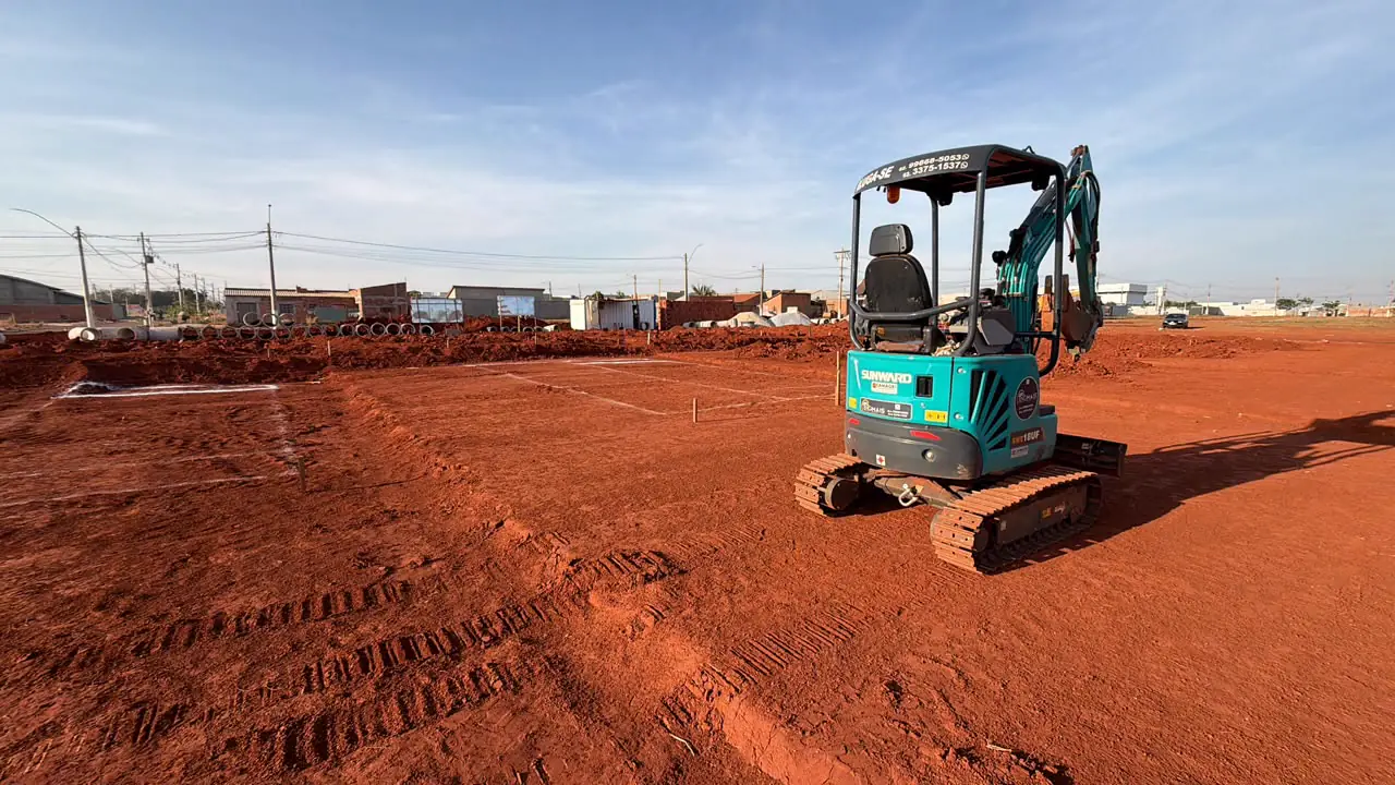 Mini escavadeira EngMais trabalhando em lote de terra vermelha